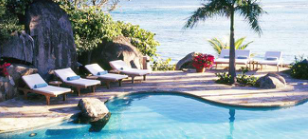 Oceanside pool with palm trees and lounge chairs.