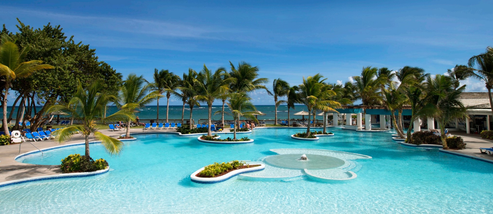 Coconut Bay in St. Lucia view of the pool with the ocean and sky in the background.