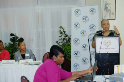 Jamaica Business Development Corporation, a woman at a podium speaks with others sitting at tables.