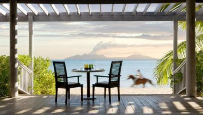 A beachfront view from the porch, with a horse and volcano in the background. At Carlisle Bay Resort.