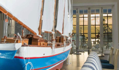 An inside view of a room with a model boat and a view of the marina out of the glass doors in the background, at Valentines Residences Resort and Marina.