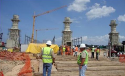 BSI Services Limited Trinidad work site with cranes and structure being built with workmen wearing bests and hard hats.