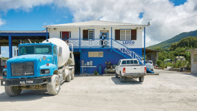 Lefco Equipment Rental. A two story building with Lefco on the side and a Cement truck and regular truck out front with someone on the second story balcony.