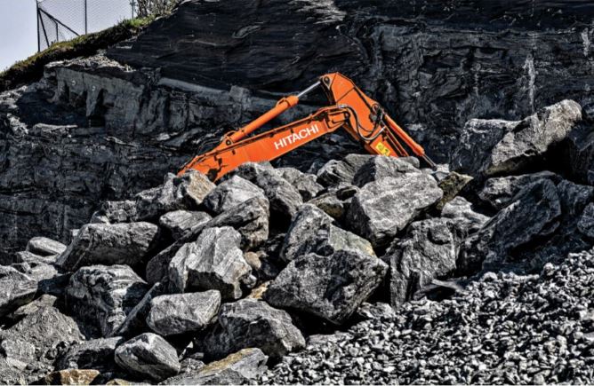 Lydford Mining. Excavator at work hillside with rocks surrounding it.