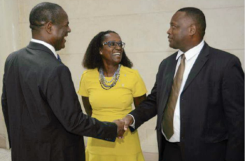 The Minister for the Ministry of Industry for Barbados shaking hands with a man and a woman standing next to him.