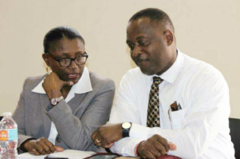 The Honorable Donville 0. Inniss, Minister of Industry sits with a woman in a suit talking.