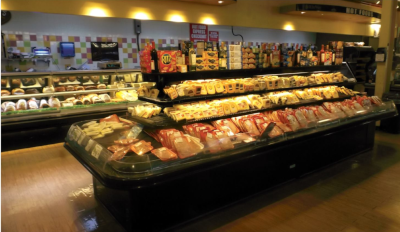 Roadtownwholesale Trading Ltd, a view of a deli with a large selection of meats and cheese on display up front and their deli counter for meats behind.