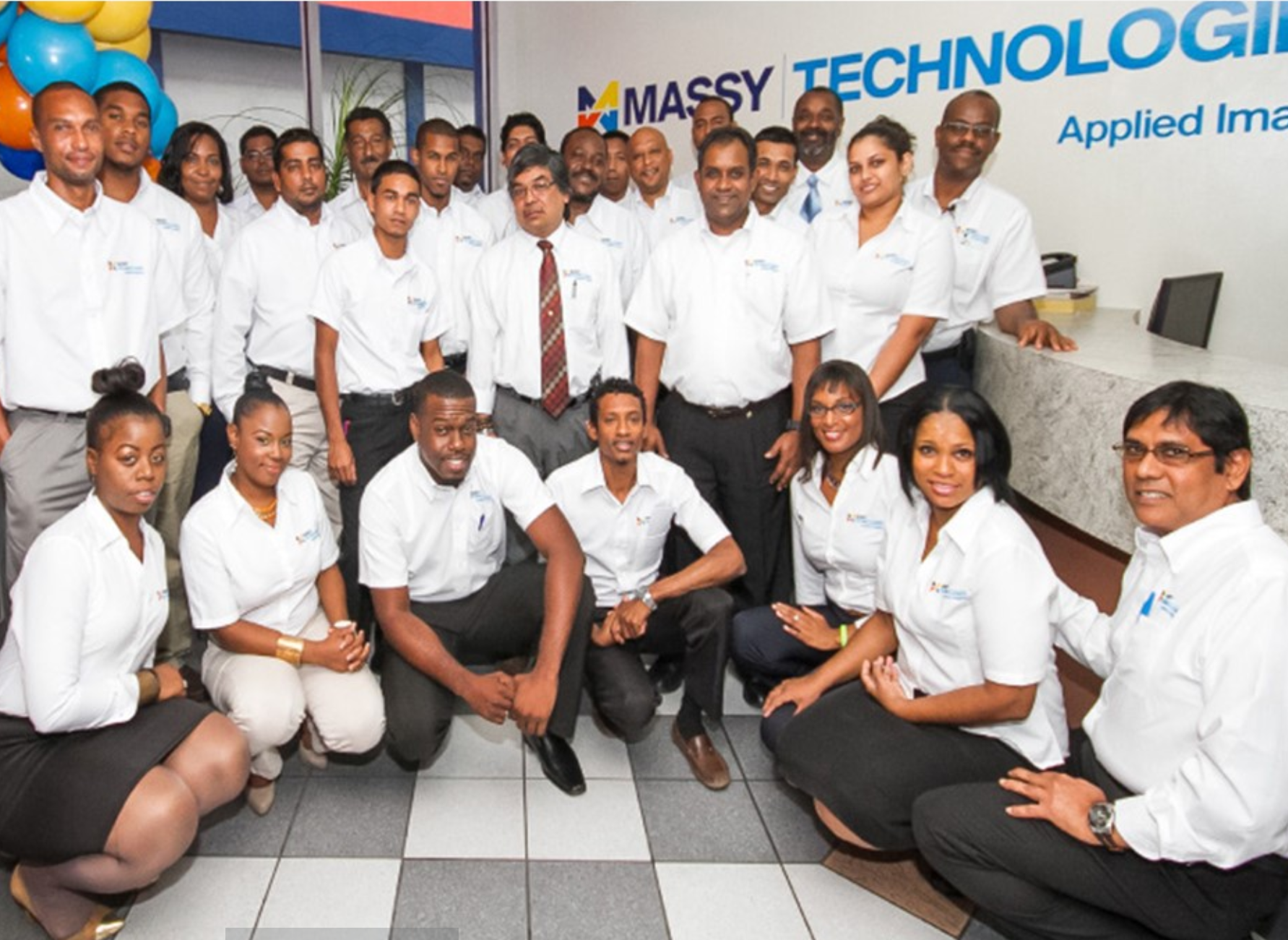A group photo of Massy Technology employees, back row standing, front row kneeling.