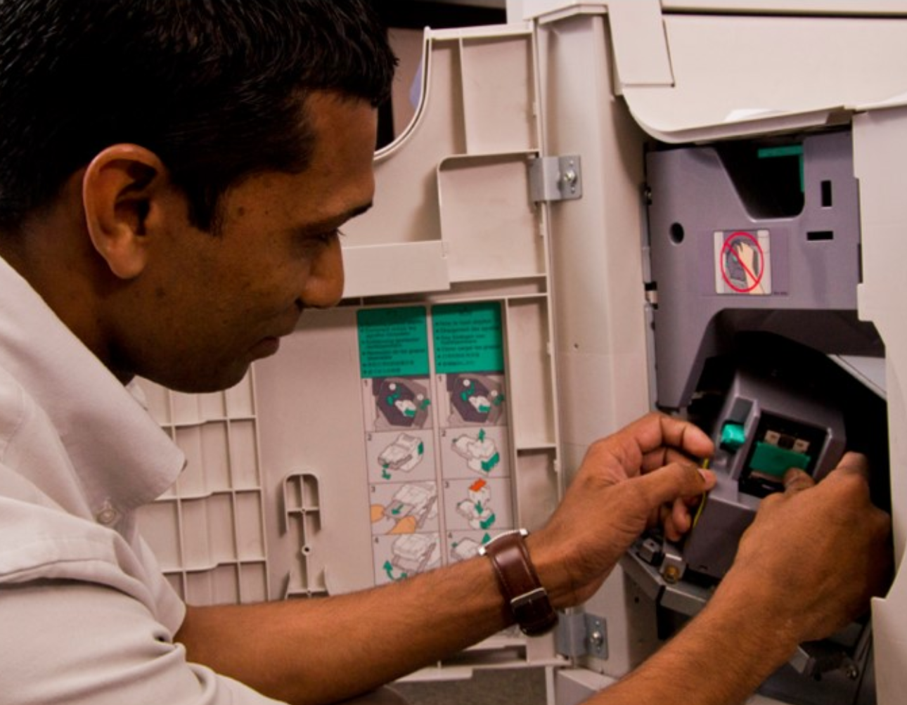 Massy Technology Applied Imaging employee working through the side panel of a piece of equipment.