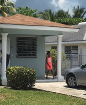 Bahamas Mortgage Corporation. A person stands on their porch by their driveway.