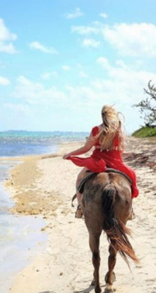 Ministry of District Administration, Tourism and Transport. A woman rides a horse on the beach along the blue waters of the Caribbean.