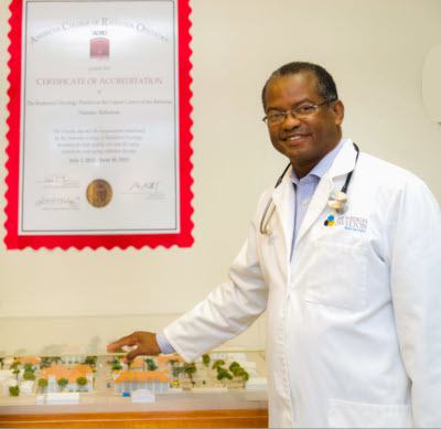 Dr. Brown standing with his hand on a model of building.