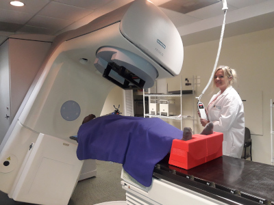 A medical employee scanning a patient laying on a table with a large rotating machine. Cancer Centre Bahamas, Medical Pavilion.