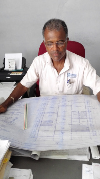 Incorporated Masterbuilders Association of Jamaica's President Humphrey Taylor sits at a desk looking over blueprints.