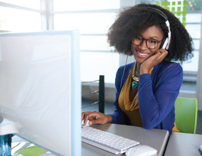 The University of the Commonwealth Caribbean. A woman sits at a desk with a headset on.