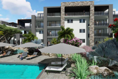 Aquarius Caribbean, a new residential project digital mockup showing a large residential building and pool with tables and chairs and landscaping.