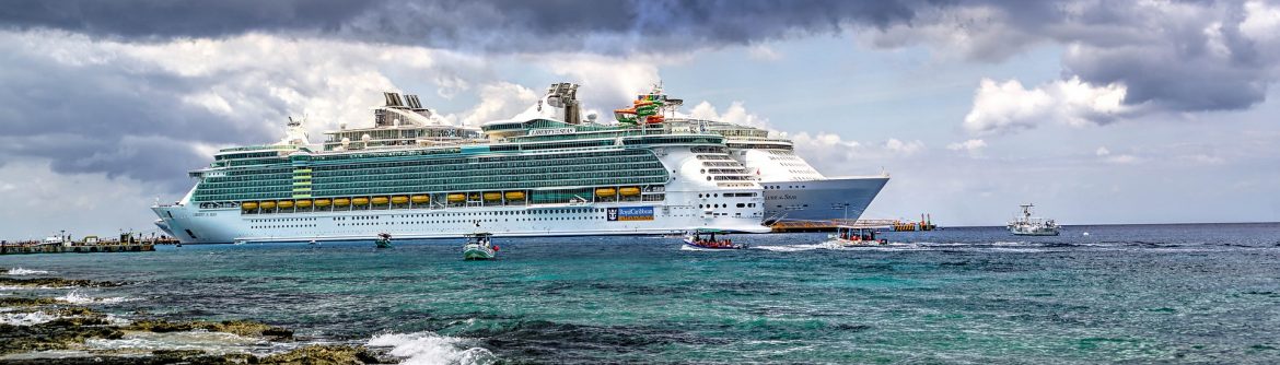 Two cruise ships docked with smaller boats around it on the water.