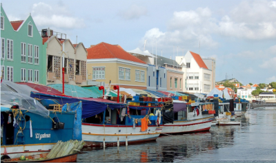 Boats docked along the water with colorful houses behind.