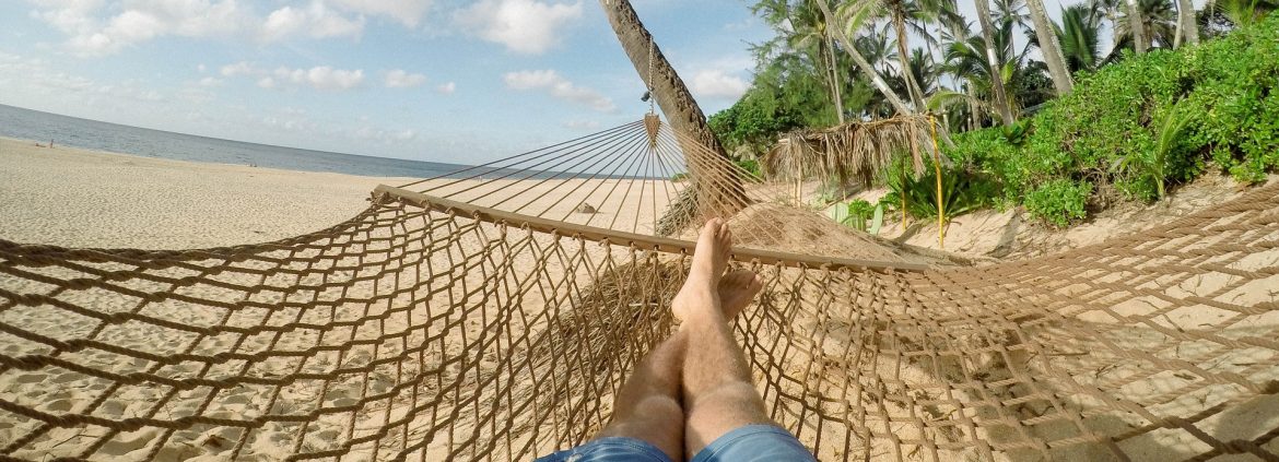 First person view of laying in a hammock on the beach.