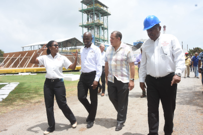 National Rums Jamaica, 4 people walking and talking at a construction site, one man wearing a blue hard hat.