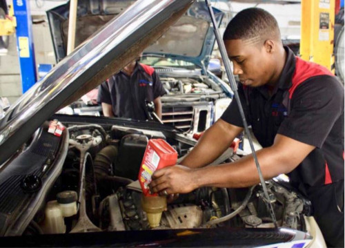 Harney Motors Ltd. Antigua. A man working on a car engine under the hood.