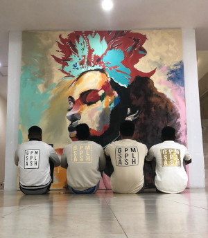 Sheraton Mall. 4 Men sitting on the floor in front of art on a wall.