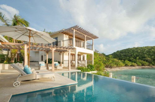 Blue Waters Resort and Spa - Antigua. The back of a house with a pool and ocean in view.