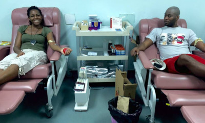 Milton Cato Memorial Hospital, Saint Vincent and the Grenadines. Two people sitting on hospital chairs giving blood.