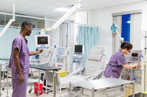 TCI Hospital - Turks and Caicos. Two employees working in a room with patient chairs and other equipment.