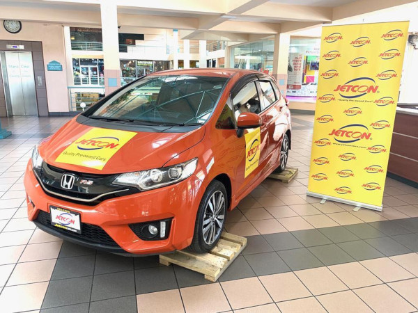 Jetcon Corporation Pre-Owned Cars. Interior of their showroom with a car and stand up banner next to it.