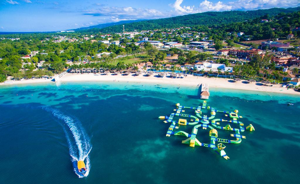 Puerto Seco Beach aerial view with a boat leaving the beach by their floating obstacle course.