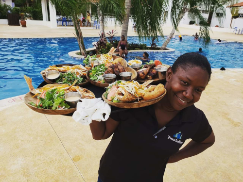 Puerto Seco Beach waitress carrying a tray full of seafood by the pool.