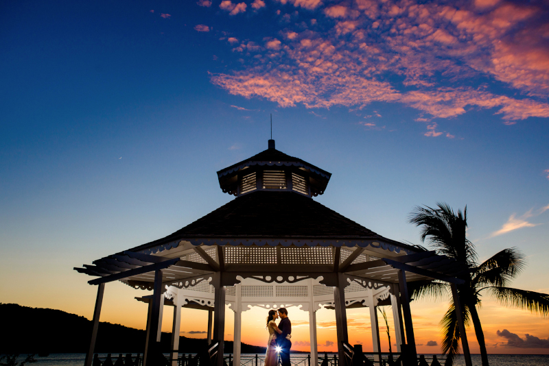 Moon Palace Jamaica, a gazebo at sunset with blue sky and a couple kissing in the middle.