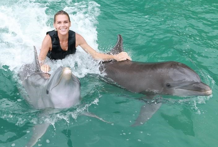 Dolphin Cove Jamaica photo of a woman getting a pull by two dolphins in the water.