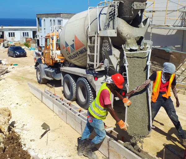 Ready-Mix Limited Barbados cement truck with two employees pouring cement.